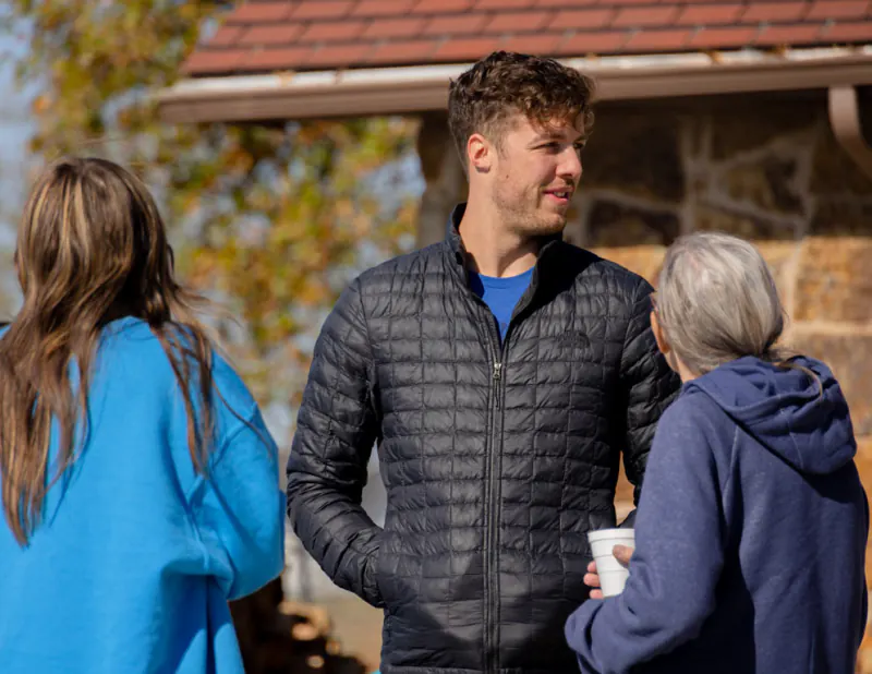 Guests chatting outside a stone building at Lake Hudson Resort